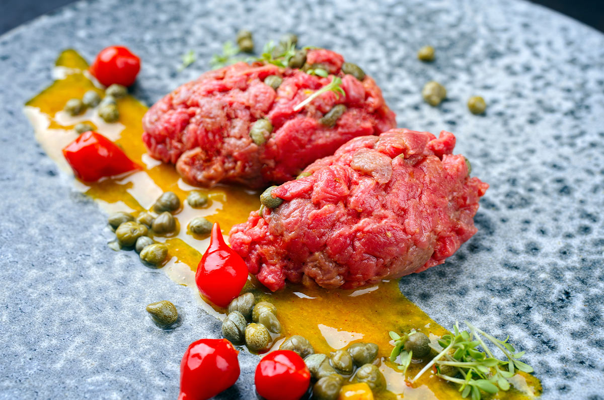 Tartare di manzo realizzata con filet mignon con capperi salsa alla senape peperoncini dolci e germogli freschi